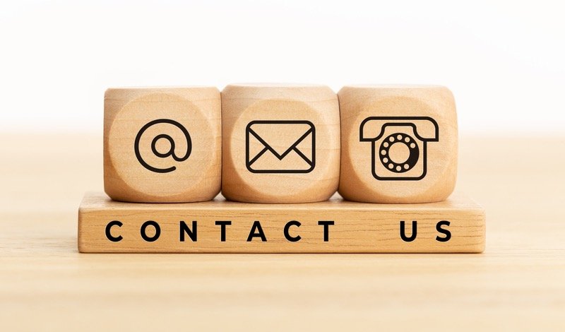 Bloques de madera con íconos de correo, mensaje y teléfono, con el texto Contact Us
